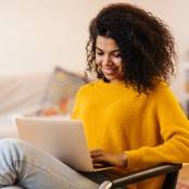 vrouw zit op stoel met laptop op schoot