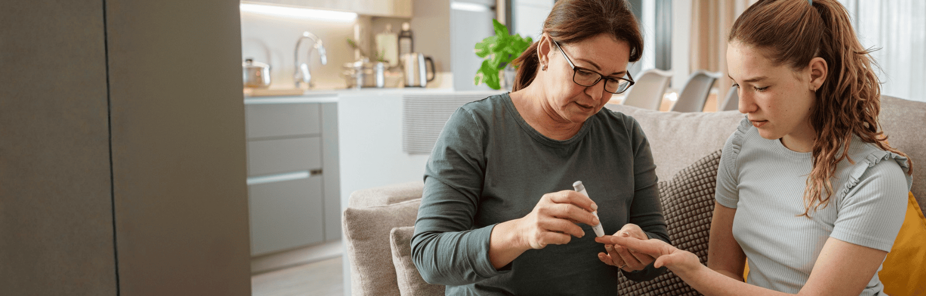 een moeder prikt dochter met diabetes pen in de vinger. De sfeer is huiselijk.